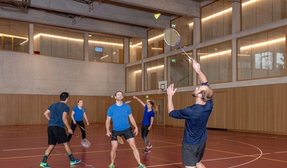 Männer und Frauen spielen Badminton in einer Turnhalle