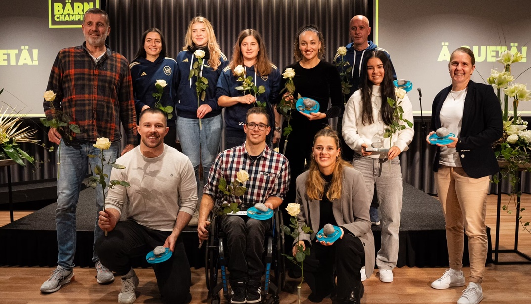 BÄRNCHAMPIONS auf einer Bühne mit weissen Rosen und blauen Auszeichnungen.