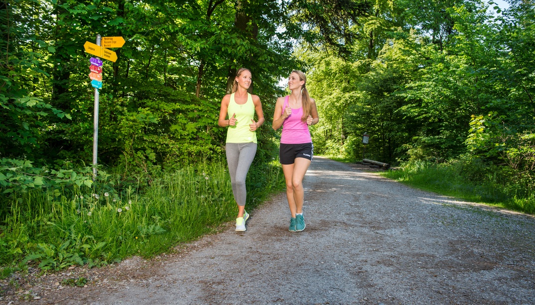 Zwei Frauen joggen nebeneinander im Wald