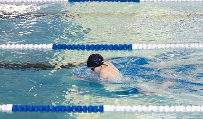 Ein Kind schwimmt in einer Schwimmbahn mit Schwimmkappe und Schwimmbrille
