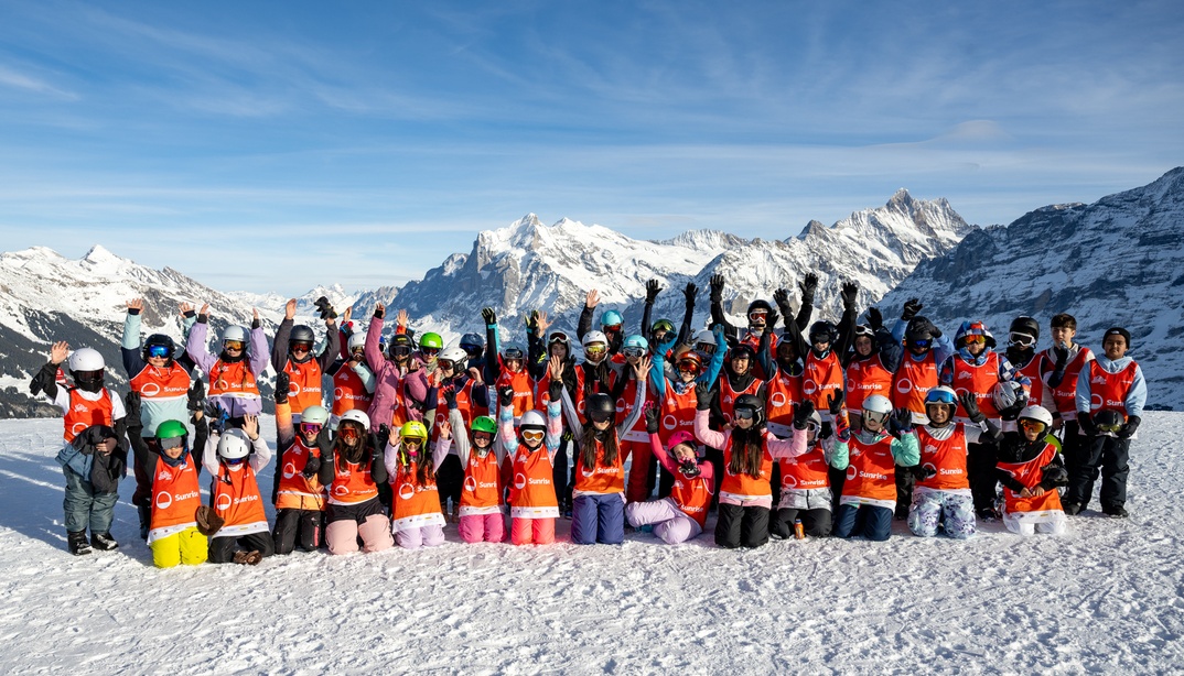 Kinder in Ski-Kleidung posieren auf einer Skipiste an den Sunrise SnowDays, im Hintergrund Berge