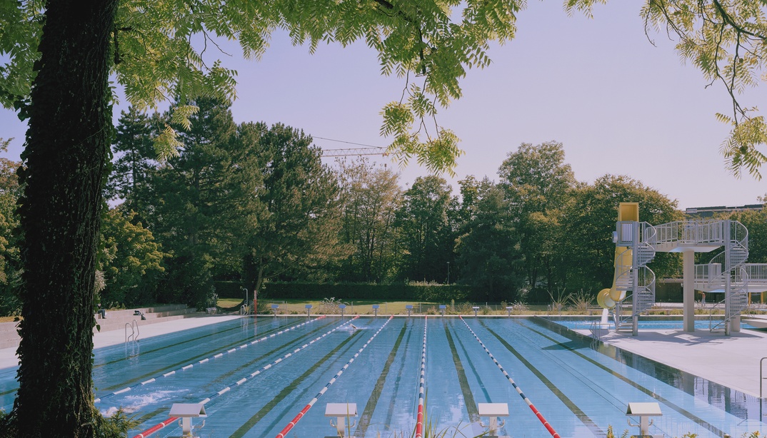50m-Becken mit Sprungturm im Freibad Wyler, im Vordergrund ein Baum