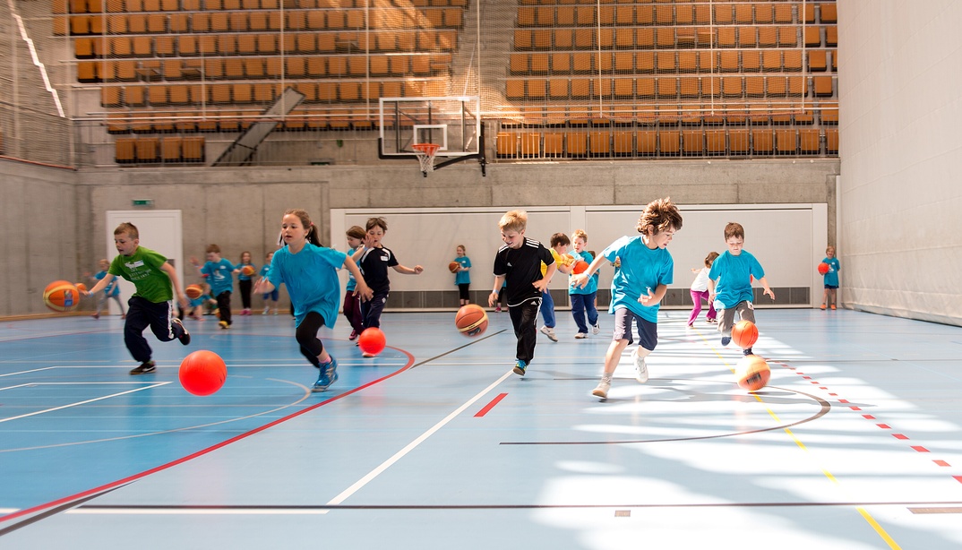 Kinder beim Ballspielen in einer Turnhalle