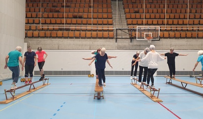 Senior*innen machen Balance-Übungen auf einem Bänkli.