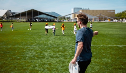Mann wirft ein Frisbee und Kinder rennen, um es zu fangen