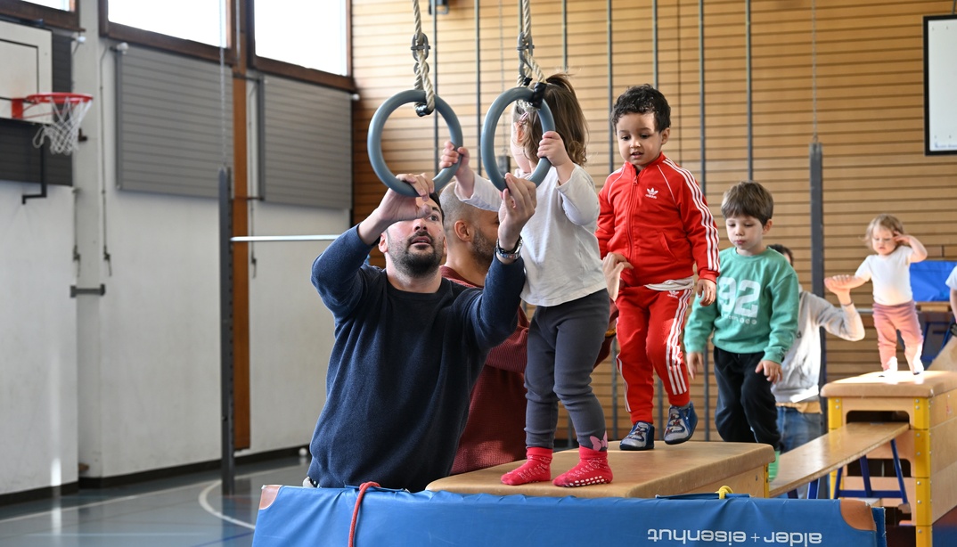 Kinder und Begleitperson beim Turnen an den Ringen