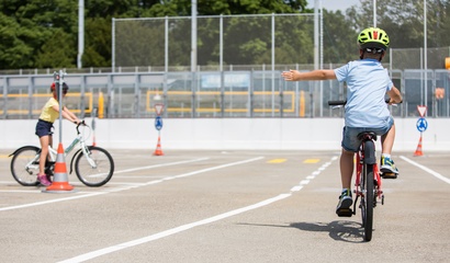 Zwei Velofahrer*innen in einem verkehrsähnlichen Umfeld.