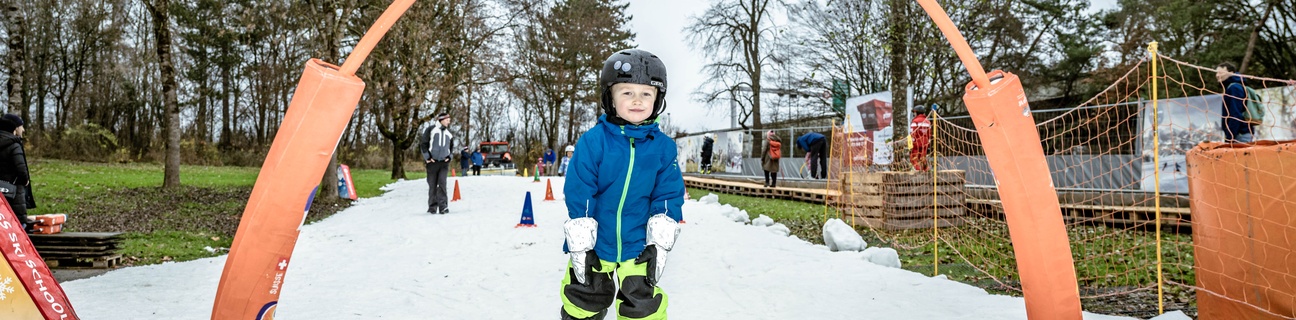 Ein Kind fährt unter einem orangen Bogen durch beim Schneespass im Weyerli