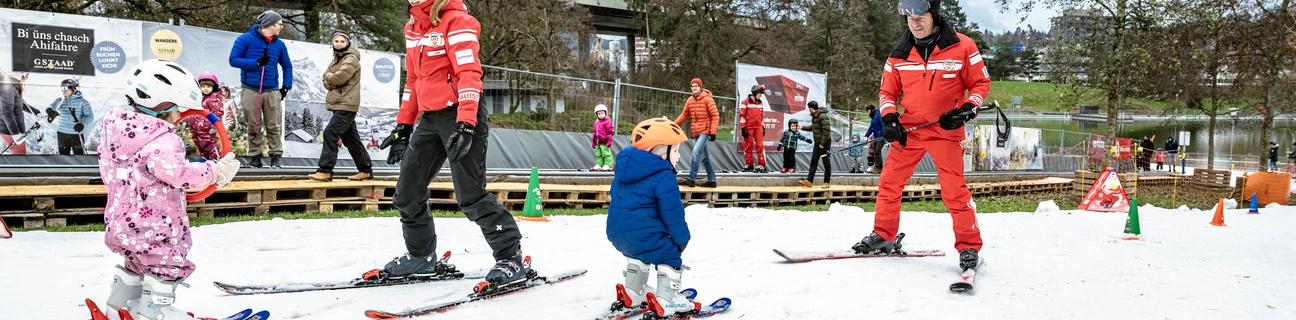 Kinder fahren Ski mit Skilehrer*innen beim Schneespass im Weyerli